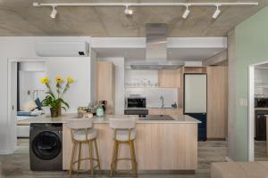 a kitchen with a sink and two bar stools at Modern penthouse living Sea Point One26 On M in Cape Town