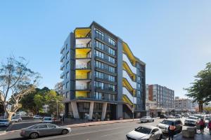 a tall building with yellow balconies on a city street at Modern penthouse living Sea Point One26 On M in Cape Town