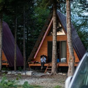 une personne assise devant une cabine dans les bois dans l'établissement Bude Mestia cottages, à Mestia