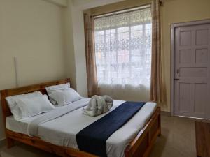 Schlafzimmer mit einem Bett und einem großen Fenster in der Unterkunft DAMEKI a unit of ME HOSPITALITY in Shillong
