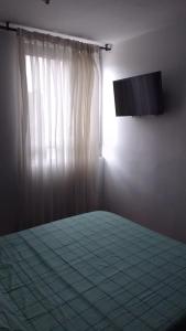 um quarto com uma cama e uma televisão na parede em Apartamento acogedor en Ibagué em Mirolindo