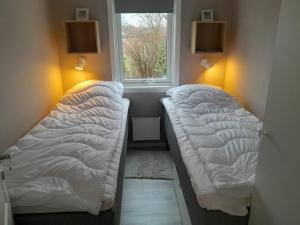 two beds in a small room with a window at Nice little cottage in picturesque Tonnersa beach village, near Halmstad in Eldsberga