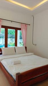 a bedroom with a large bed with white sheets and a window at Pai Family House in Pai