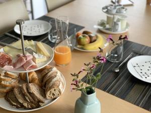 einen Tisch mit Teller mit Speisen, Brot und Orangensaft in der Unterkunft L'Impasse de Lincé in Sprimont