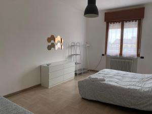 a bedroom with a bed and a dresser and window at Torrione view apartment in Spilamberto