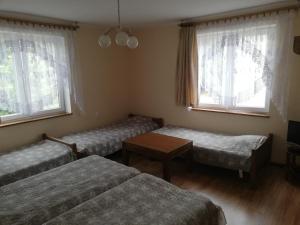 a room with two beds and a table and two windows at Pokoje Augustowskie in Augustów