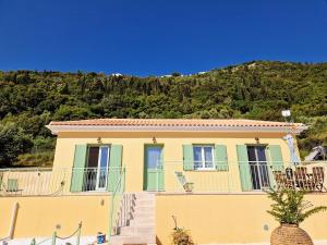 a yellow house with a mountain in the background at Phileo Villas in Platithriás