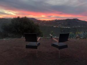 dos sillas sentadas en la cima de una colina al atardecer en CASA TEJERA II en Las Palmas de Gran Canaria