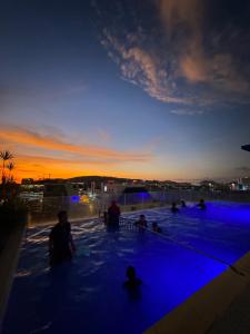 a group of people sitting in a swimming pool at sunset at Opulent Nights Sky Hotel 2BR Family Stay KK in Kota Kinabalu