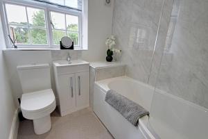 a bathroom with a toilet and a tub and a sink at One Norwood - Grade 2 Listed, Central 3 Bed in Beverley