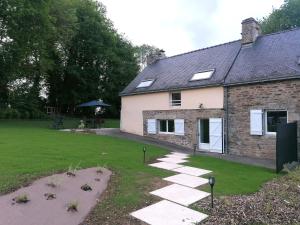 a house with a stone walkway next to a yard at Les gîtes de l'étang de la Forêt 2 in Brandivy