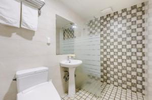La salle de bains blanche est pourvue de toilettes et d'un lavabo. dans l'établissement Pine Hill Hotel, à Seogwipo