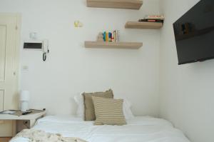 een slaapkamer met een bed met witte lakens en boeken bij MaCri di TSS' - Per coppie, colazione in balcone, intimo e relax in Levico Terme