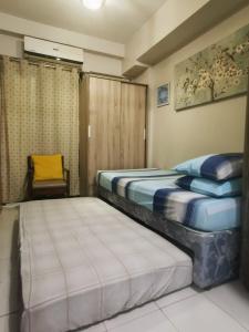 a bedroom with two beds and a chair in it at A cozy, relaxing condo at city center in Davao City