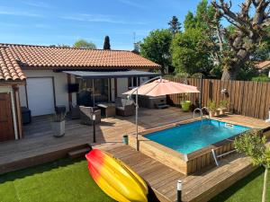 a backyard with a pool and a deck with an umbrella at Vill'Armonie in Biscarrosse