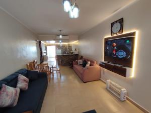 sala de estar con sofá azul y TV en Palmera Chalets Owners Best Vacation Group Families only, en Ain Sokhna