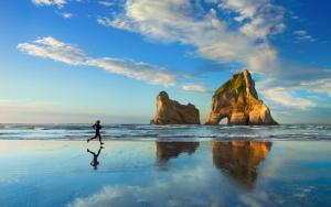 um homem a caminhar numa praia com duas grandes rochas em sa janna em Orosei
