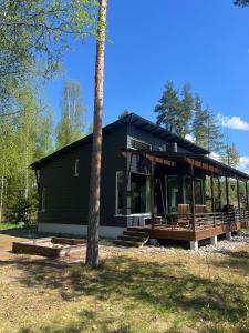 a black house with a porch and a tree at Pirttiranta in Iitiä