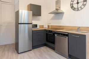 eine Küche mit Küchengeräten aus Edelstahl und einer Uhr an der Wand in der Unterkunft Logement de charme en plein coeur d'Avignon in Avignon