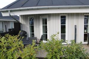 a house with a black roof and chairs on a porch at Skøn ferielejlighed midt i Marielyst by in Marielyst