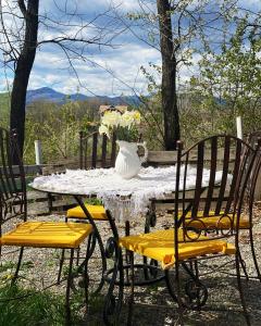 uma mesa com cadeiras amarelas e um vaso branco sobre ela em Casa Mariei - Vila Breaza em Nistoreşti