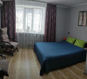 a bedroom with a bed and a chair and a window at Smart Apartment на Соборной 23 in Kremenchuk