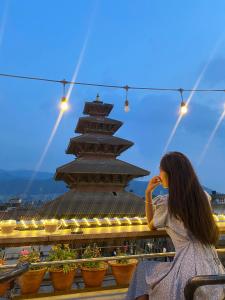 a woman sitting on a bench in front of a pagoda at Annapurna Guest House and Rooftop Restaurant in Bhaktapur