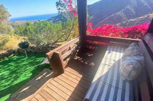 a balcony with a view of the ocean and flowers at Romantic Mountain cabin with Spa in Caserío Carraspite +12 photos