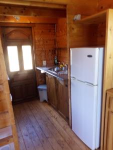 a kitchen with a white refrigerator and a window at Romantic Mountain cabin with Spa in Caserío Carraspite