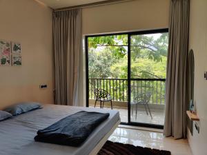 a bedroom with a bed and a balcony with a large window at The Marigold Villa in Pune