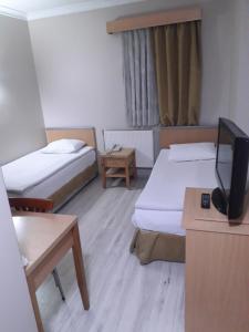 a room with two beds and a flat screen tv at OTEL AMİLLER in Erzurum