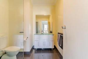 y baño con aseo blanco y lavamanos. en Luxurious 3 bedroom beachfront - panoramic views, en Port Adelaide