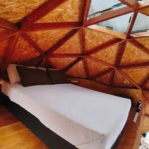 Bett in einem Zimmer mit Holzdecke in der Unterkunft Glamping Ibanazk in Ibagué