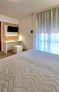 a bedroom with a large bed and a television at Hotel Panorama in Lido di Jesolo