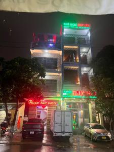 un edificio con letreros de neón y coches aparcados delante de él en Nhà Nghỉ Thiên Tân 2 en Quang Ngai