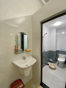 W łazience znajduje się umywalka, toaleta i lustro. w obiekcie Nhà Nghỉ Thiên Tân 2 w mieście Quang Ngai