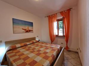 Schlafzimmer mit einem Bett und einem Fenster mit orangefarbenen Vorhängen in der Unterkunft Appartamenti Fetovaia Elicriso in Fetovaia