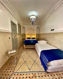 a large bedroom with a blue bed and a table at Riad Magnolia & SPA in Marrakech