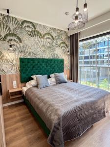 羅戈沃的住宿－Baltic Seasons by Alluxe Boutique Apartments，一间卧室配有一张大床和绿色床头板