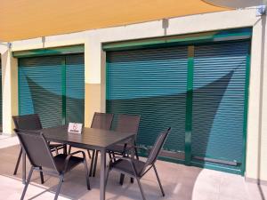 a table and chairs in front of a building with windows at Szárszó Apartmanok in Balatonszárszó