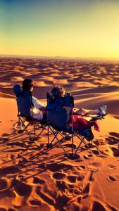 two people sitting in chairs in the desert at Horaz Merzouga Camp in Merzouga