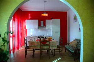 uma cozinha com paredes vermelhas e uma mesa e cadeiras em B&B Villa Magna Grecia em Lazzaro