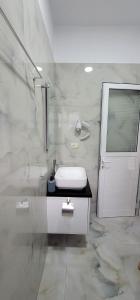 a white bathroom with a sink and a shower at Vila Ori in Ksamil