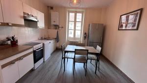 uma cozinha com uma mesa e cadeiras e um frigorífico em Appartement T4 70m2 - meublé - centre ville - proche Thermes em Lons-le-Saunier