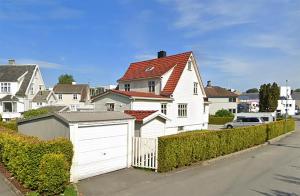 una casa blanca con garaje frente a una calle en Koselig studioleilighet i Sandnes sentrum en Sandnes