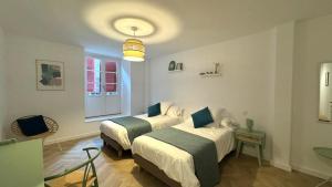 a room with two beds and a table and a window at Maison LAURENTZENIA in Saint-Jean-Pied-de-Port