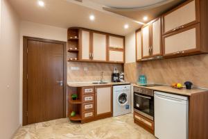 a kitchen with wooden cabinets and a washer and dryer at Апартамент за гости ВениАн in Velingrad +5 photos
