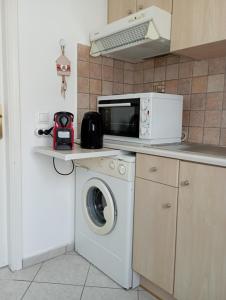 cocina con lavadora y microondas en Captain's Nest, en Ándros