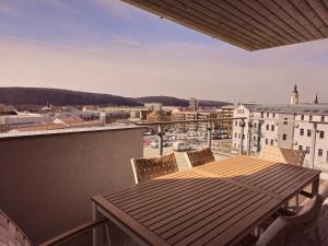 een houten tafel op een balkon met uitzicht op de stad bij 1880 Lofthaus & Apartmenthaus in Gera