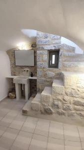 a stone bathroom with a sink and a tv on a wall at Rafaela 2 floor suite in Pyrgos Dirou